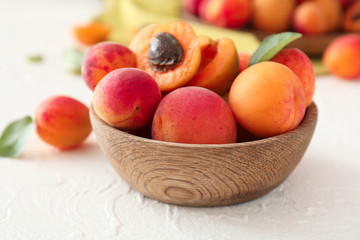 Bowl with ripe sweet apricots on white table