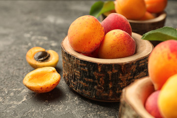 Creative wooden bowl with ripe sweet apricots on grunge background