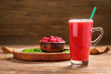 Glass of tasty raspberry smoothie on wooden table