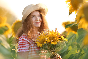 Beautiful redhead woman in sunflower field on sunny day