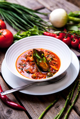 Mussel cooking with lemon and herbs in clay pot over wood background
