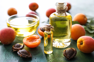 Bottles with essential oil and fresh apricots on table