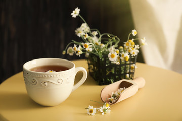 Cup of delicious camomile tea on table