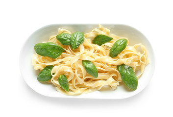 Plate of delicious pasta with basil on white background