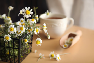 Basket with beautiful camomile flowers on table
