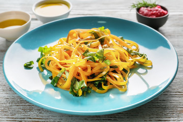 Plate of delicious pasta with basil on wooden table, closeup