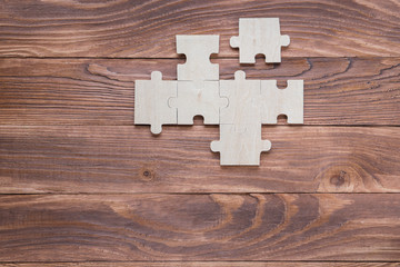 Incomplete wooden puzzles on brown wooden desk, top view, flat lay.