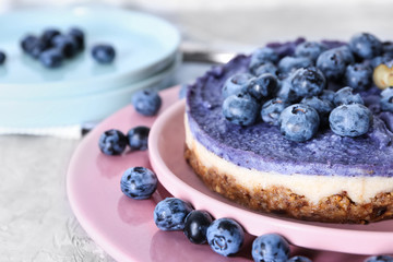 Plate with tasty blueberry cheesecake on light table, closeup