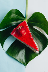 Piece of delicious strawberry cake with monstera leaf