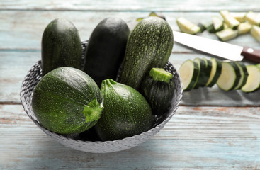 Bowl with fresh zucchini on wooden table