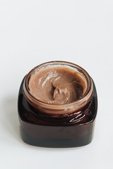 Chocolate cream in small jar on white background