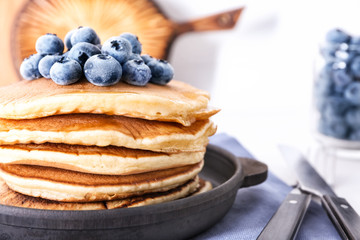 Frying pan with tasty pancakes and blueberries, closeup