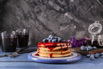 Plate with tasty pancakes, jam and blueberries on wooden table