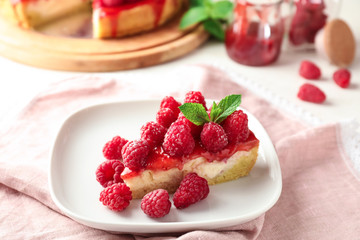 Plate with piece of delicious raspberry cheesecake on table