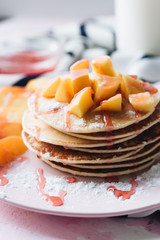 Stack of delicious homemade pancakes with sauce and sliced appl
