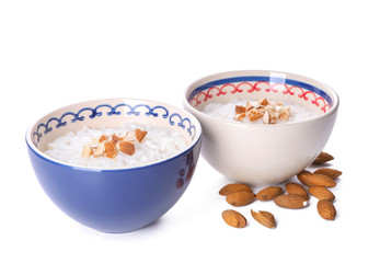Bowls with delicious rice pudding and nuts on white background