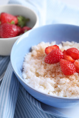 Bowl with delicious rice pudding and strawberry on table, closeup