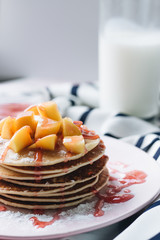 Stack of delicious homemade pancakes with sauce and sliced appl
