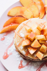 Stack of delicious homemade pancakes with sauce and sliced appl