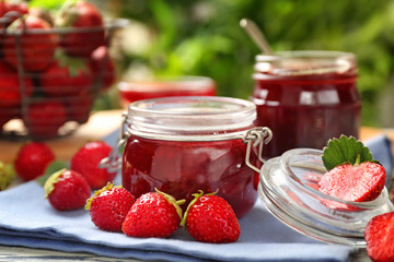Glass jar with delicious strawberry jam on table