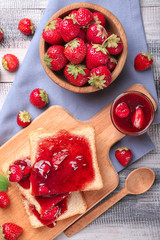 Composition with slices of bread and delicious strawberry jam on wooden table