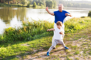 Grandfather and little grandson  practice Tai Chi Chuan outdoors.  Chinese management skill Qi's...