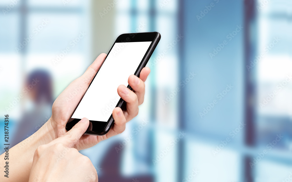 Fototapete Hand click mobile phone with blur office background bokeh light,White screen mock up template for adding your design or your text.