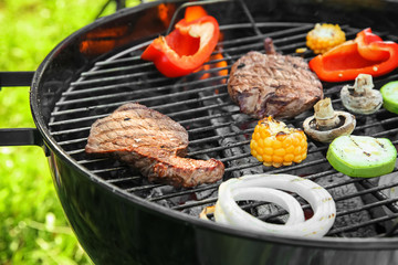 Tasty meat with vegetables on barbecue grill, closeup