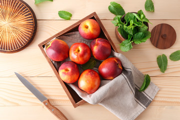 Wooden box with fresh sweet peaches on table