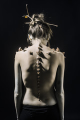 Girl with fantasy style make up. Woman with thorns on skinny back and shoulders fantasy creature....