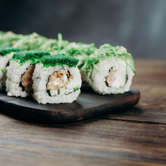 Sushi restaurant menu, Japanese food, gourmet meals. Rolls with smoked tuna and philadelphia cheese on wooden tray, close up