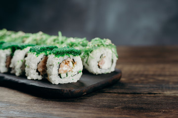 Japanese restaurant, sushi plate. Delicious seafood maki rolls on black wooden tray, copy space