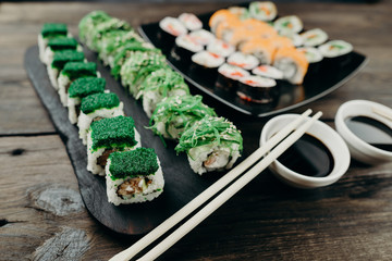 Japanese seafood cuisine, food art, restaurant menu photo. Delicious appetizing sushi set served on black plates on dark wooden table