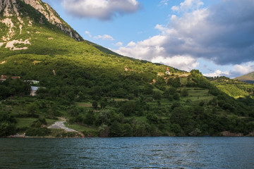 Onboard morning Lake Komani ferry from Fierza to Koman in Albania - tiny church at the foot of the mountain