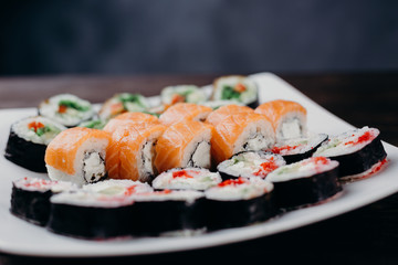 Food art, traditional  japanese seafood, restaurant menu photo. Tasty great colorful set of fresh sushi maki rolls with salmon, tuna and avocado served on white porcelain pate