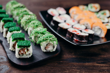 Japanese restaurant menu photo, seafood, national cuisine. Delicious assortment of sushi. Appetizing rolls served on black plate, selective focus