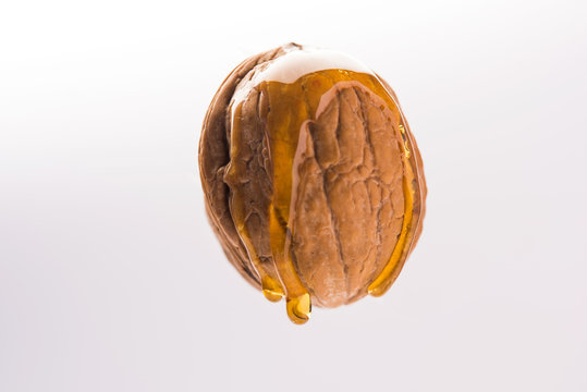 Golden walnut oil drop dripping fromnwhole Akrod/akhrot dry fruit, flying in the air isolated