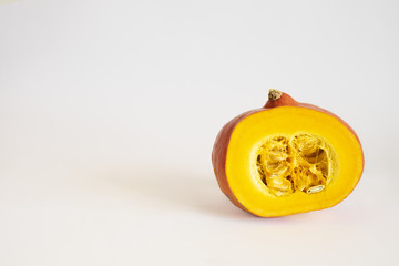 Isolated half cut orange red kuri hokkaido japanese squash over the white background with space on a left