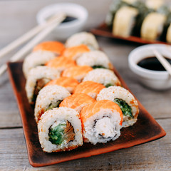 Japanese restaurant, traditional cuisine. Appetizing set of sushi rolls served on clay plates, chopsticks and sauce bowls