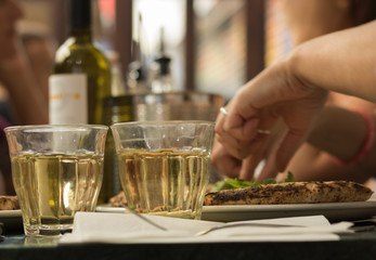 Simple meal for two people: two glasses of white wine and pizza.