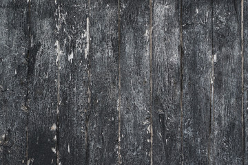 Grungy background of peeling flaking black paint on wooden boards