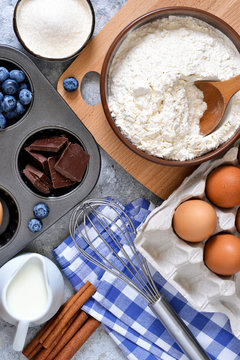 Food background. Ingredients for baking: flour, eggs, berries, chocolate on a concrete background.