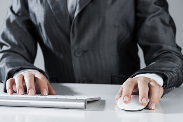 Closeup of businesswoman hand typing on keyboard with mouse on w