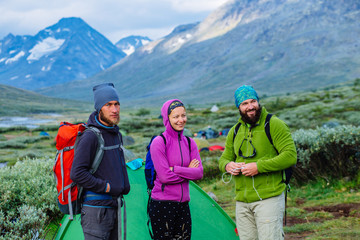 Three climber before climbing the mountains. man with a backpack near the camp near a tent in the mountains in summer. Team hikers with backpacks before leaving a camping. Weekend in Norway