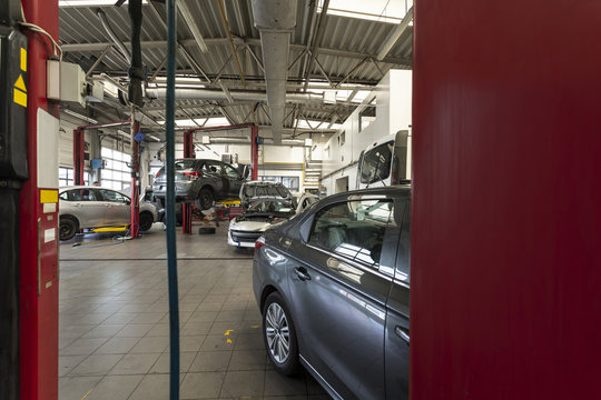 Luxury Cars Being Repaired In A Modern Garage. View Through Red Door