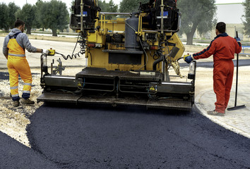 Fototapeta na wymiar Workers regulate tracked paver laying asphalt heated to temperatures above 160 ° pavement on a runway
