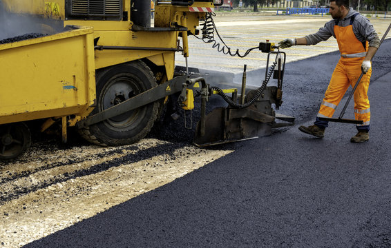 Machine operator to spread asphalt, intervenes on the control panel to adjust the asphalt paving
