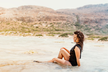Fototapeta na wymiar beautiful latin caucasian woman wearing one piece swimming suit, smiling on sandy beach enjoying waves
