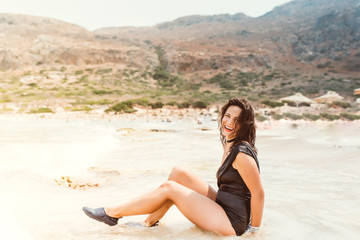 Fototapeta na wymiar Summer lifestyle portrait of beautiful young woman on sandy beach
