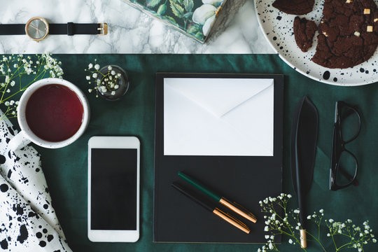 Top view on mockup of envelope and smartphone next to cup of coffee